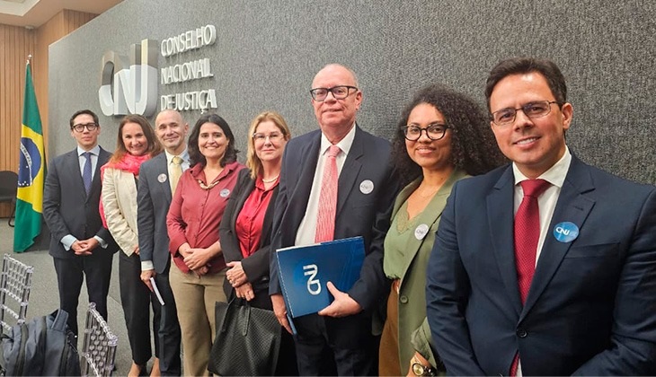 A imagem mostra um grupo de participantes posando para foto em frente ao painel com a identificação do Conselho Nacional de Justiça (CNJ). Entre eles estão magistrados e representantes de tribunais estaduais que participaram da 4ª Reunião da Rede das Unidades de Monitoramento e Fiscalização (UMFs). Os participantes estão alinhados lado a lado, trajando roupas sociais e usando crachás de identificação, em ambiente institucional na sede do CNJ, em Brasília.