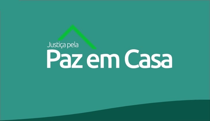 Card institucional com fundo em tom verde-água. Na parte superior central, há um símbolo gráfico em verde que lembra o formato de um telhado de casa, sugerindo a ideia de proteção e lar. Logo abaixo, em letras brancas, está o texto: “Justiça pela Paz em Casa”, com destaque maior para a expressão “Paz em Casa”.   O rodapé da imagem possui uma faixa curva em verde mais escuro, criando um efeito visual de base para o card. O design é simples, limpo e institucional, remetendo a uma campanha voltada à promoção da paz no ambiente doméstico.